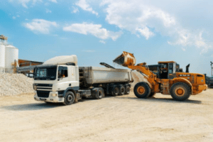 un Trax rempli du matériel de chantier dans un camion benne